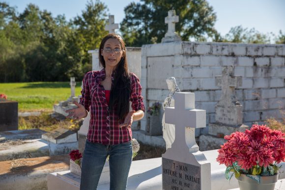 A woman speaks in front of a cemetery